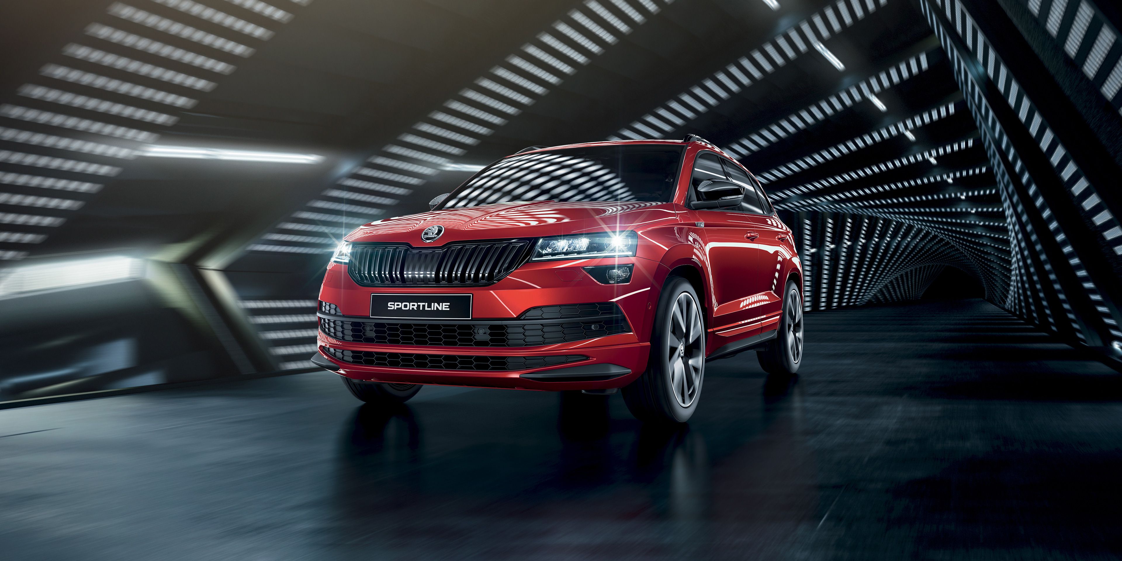 Shihet një Škoda Karoq Sportline e kuqe rrethuar nga dritat