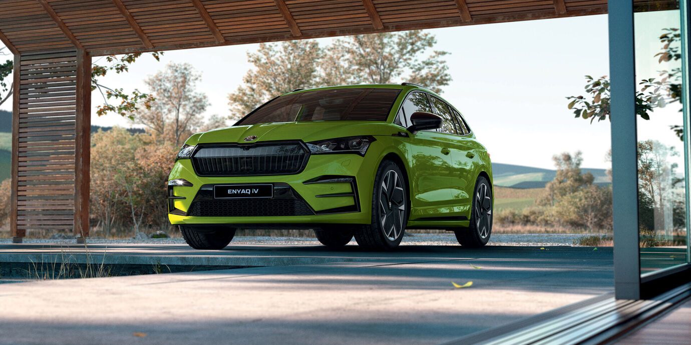 Një grua dhe një djalë duke qëndruar pranë bagazhit të një Škoda Kodiaq. Mbas tyre shihet një lumë dhe male